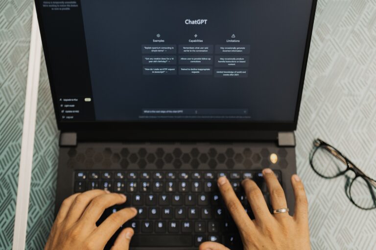 Manos escribiendo en una notebook con un asistente de IA en pantalla