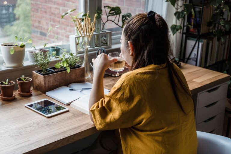 Mujer haciendo una pausa consciente con un mate junto a la ventana